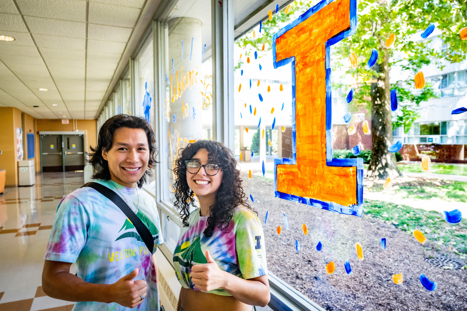 students smiling in front of decorated window