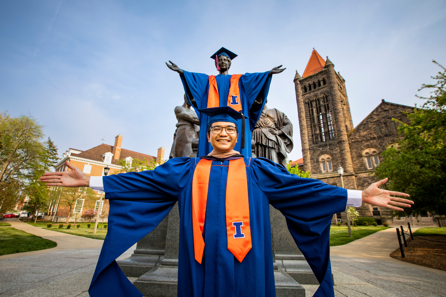 student in graduation gown in front of alma statue