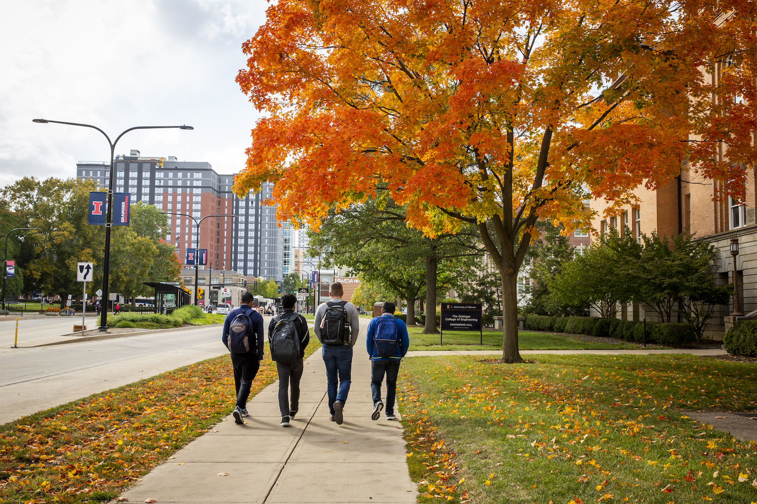 students walking on campus sidewalk in fall