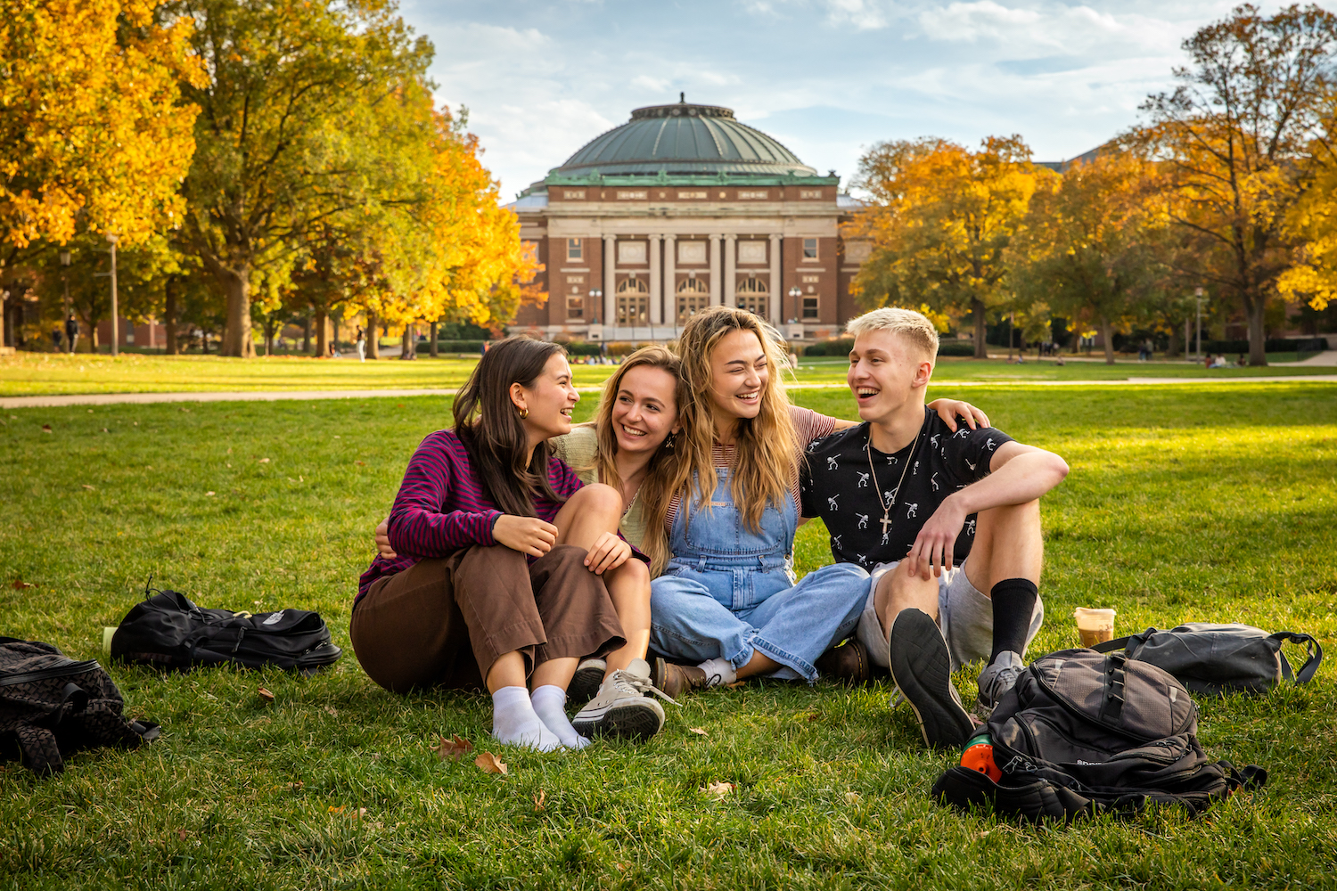students sitting on campus quad smiling